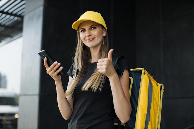 Corriere donna con telefono cellulare in cerca di consegnare l'indirizzo del cibo da un ristorante