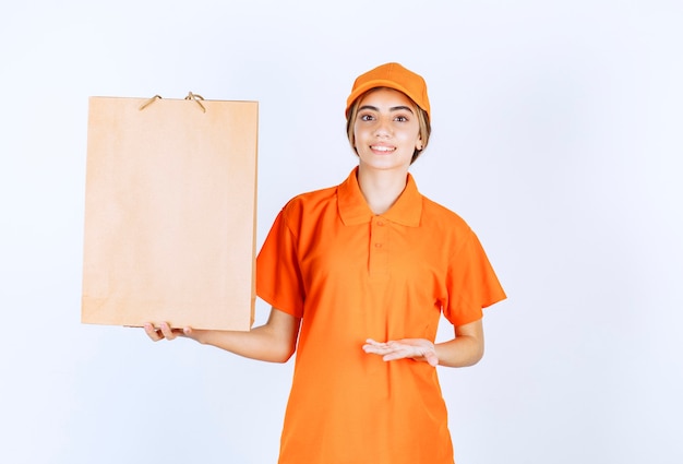 Corriere femminile in uniforme arancione che consegna una borsa della spesa di cartone