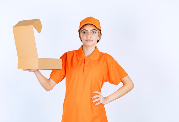 Corriere femminile in uniforme arancione che tiene una scatola di cartone aperta