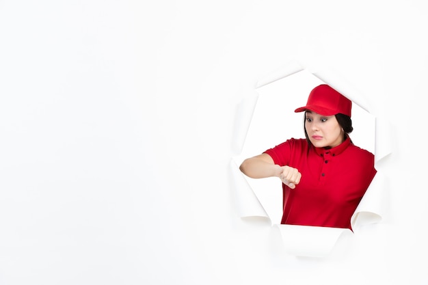 Corriere femminile in uniforme rossa che controlla il tempo su bianco