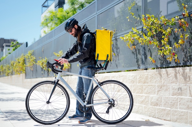 Corriere in bicicletta che consegna cibo in città utilizzando lo smartphone
