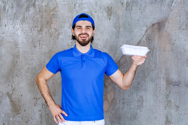 Corriere in uniforme blu con in mano una scatola di plastica da asporto