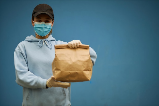 Corriere ragazza con maschera medica e guanti medici su sfondo blu