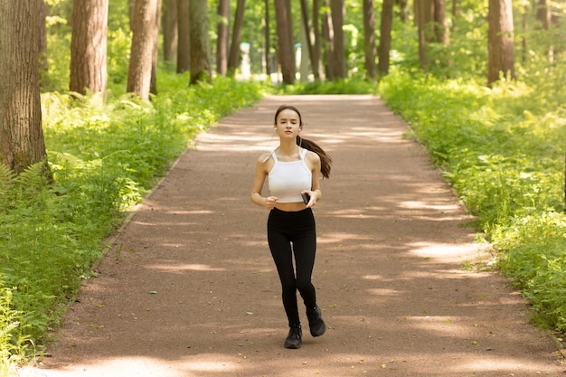 Corsa mattutina nel parco Giovane ragazza in cuffia va a fare sport