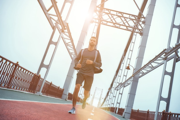 Corsa mattutina per tutta la lunghezza di un uomo giovane e sano in abbigliamento sportivo che fa jogging sul