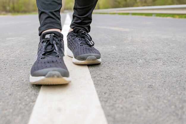 Corsa mattutina. Piedi che corrono durante la corsa, Runner in scarpe da ginnastica nere corre sull'asfalto.