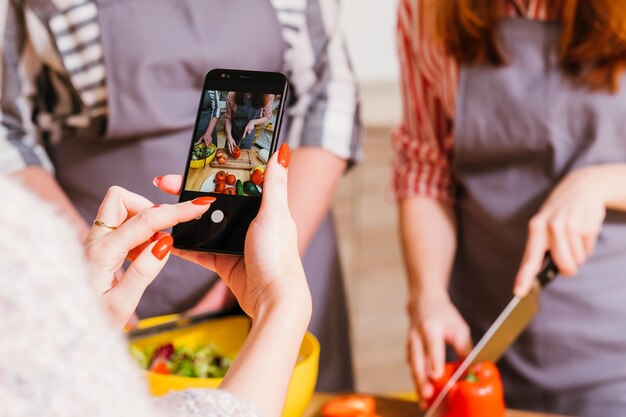 Corso di cucina online Assistente femminile che filma le donne che preparano insalata di verdure Sfoca lo sfondo