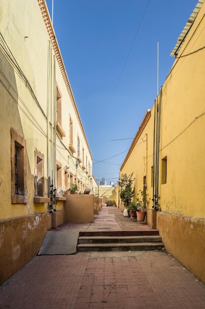 Cortile centrale di un quartiere case gialle con scale in mattoni e rampe di piante in vaso fuori dal cielo blu chiaro