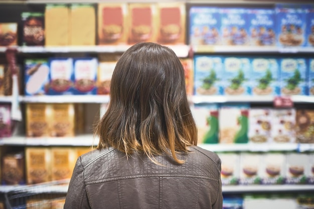 Cosa comprare Inquadratura posteriore di una giovane donna che fa la spesa in un negozio di alimentari