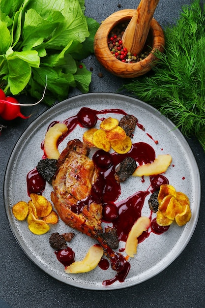 Cosce d'anatra arrosto al forno con frutta e patate con vista dall'alto di verde e ingredienti