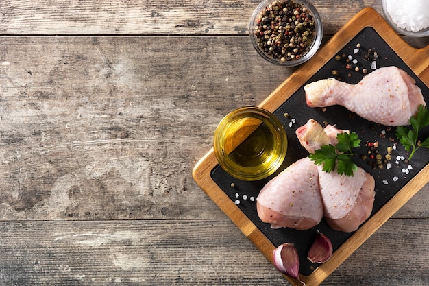 Cosce di carne di pollo cruda con spezie ed erbe aromatiche sul tagliere Vista dall'alto Spazio di copia