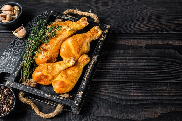 Cosce di pollo affumicate con erbe e spezie. Fondo in legno nero. Vista dall'alto. Copia spazio.