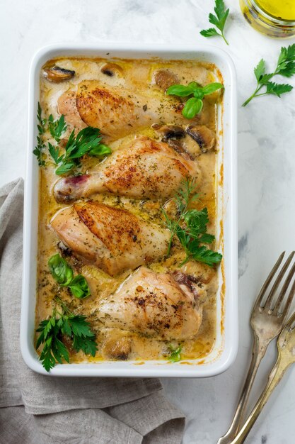 Cosce di pollo al forno in salsa di crema di senape con aglio e funghi su un fuoco leggero