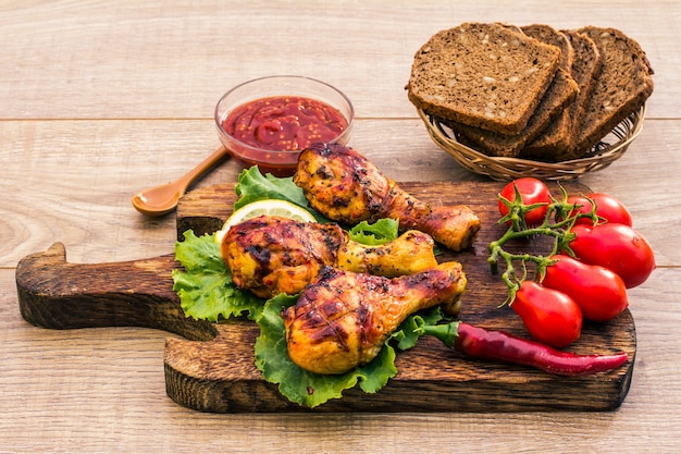 Cosce di pollo alla griglia arrostite alla griglia e foglie di lattuga sul piatto con salsa di pomodoro in una ciotola