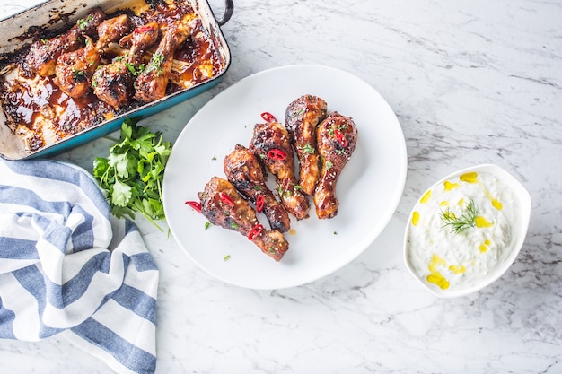 Cosce di pollo alla griglia arrosto e barbecue su piatto bianco con decorazione di erbe.