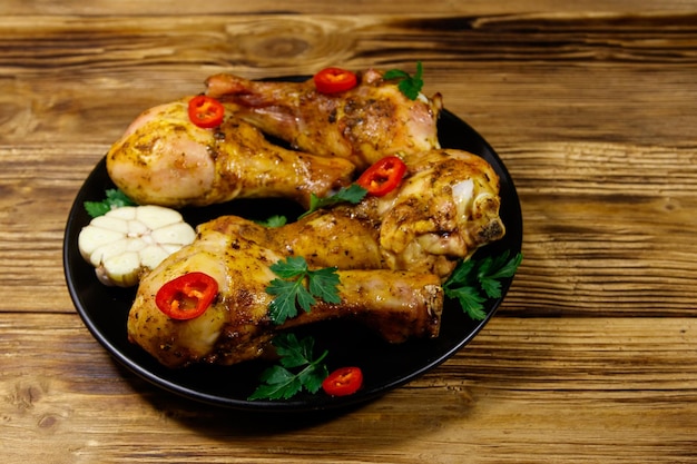 Cosce di pollo arrosto con spezie in un piatto nero su un tavolo di legno