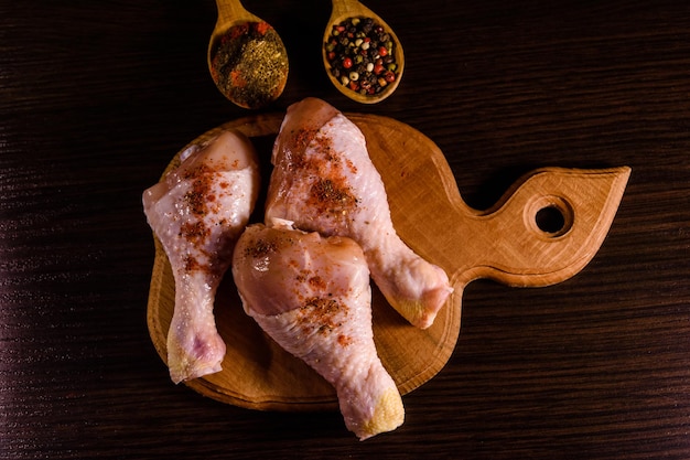 Cosce di pollo con le diverse spezie sul tagliere di legno Vista dall'alto