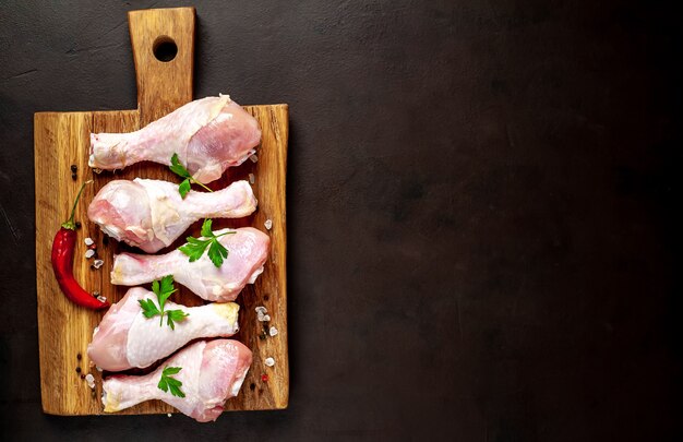 cosce di pollo crudo con spezie su uno sfondo di pietra