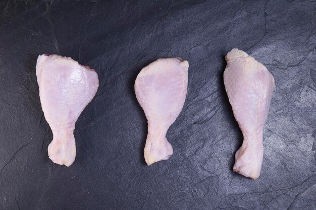 Cosce di pollo fresche su un primo piano scuro del fondo.