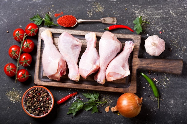 Cosce di pollo fresche sulla tavola di legno con ingredienti per cucinare, vista dall'alto