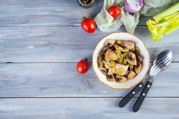 Cosce di pollo in umido con funghi, sedano, cipolla e pepe. Mescolare il pollo fritto su fondo in legno