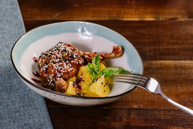 Coscia di pollo al forno con salsa e frutta sullo sfondo di legno