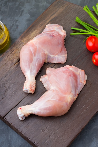 Coscia di pollo intera cruda senza pelle disposta in una tavola di legno