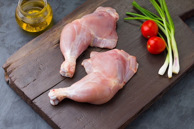 Coscia di pollo intera cruda senza pelle disposta in una tavola di legno