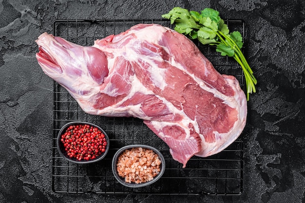 Coscia di spalla di agnello crudo fresco sul tavolo da cucina pronto per la cottura Sfondo nero Vista dall'alto