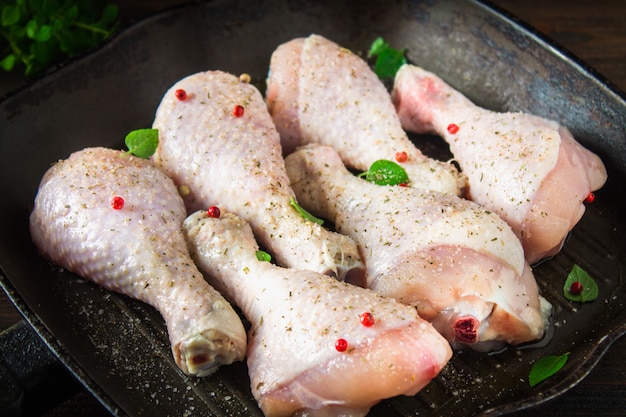 Coscie di pollo crudo in una padella su un tavolo di legno. Ingredienti a base di carne per cucinare