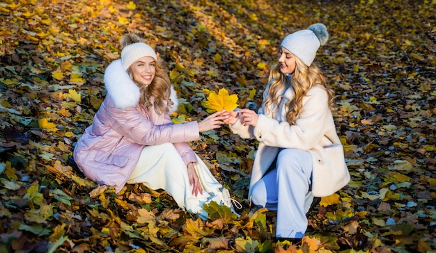 Così bello. accogliente e confortevole. moda stagione autunnale. bellezza e stile femminile. donne con i capelli lunghi nella foresta autunnale con foglie. ragazze su sfondo di foglie cadute secche. indossa vestiti caldi.