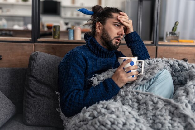 Così caldo. Giovane infelice che si tocca la fronte mentre sente la febbre