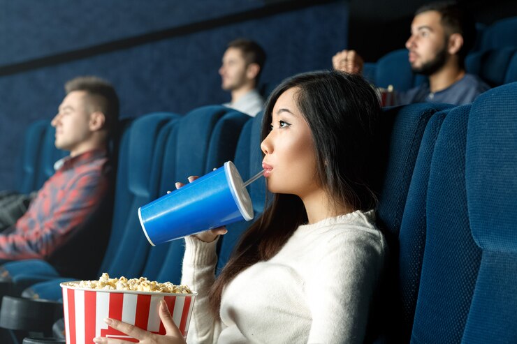 Così divertito. Ritratto di una giovane donna asiatica che beve attentamente la sua bevanda guardando film al cinema locale