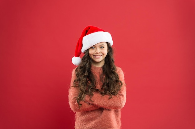 Così felice tempo per le vacanze di Natale piccola ragazza con cappello da Babbo Natale allegro bambino sfondo rosso inverno moda bambino preferito vacanza invernale divertendosi piccolo Babbo Natale felice per il nuovo anno