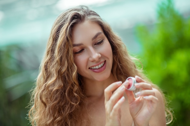 Cosmetici biologici. Giovane donna sveglia che tiene il balsamo per le labbra in mano