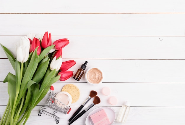 cosmetici con tulipani rosa su fondo di legno bianco