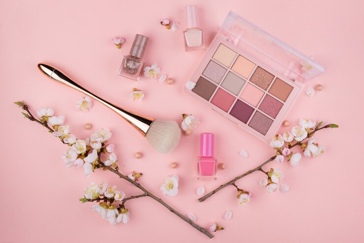 Cosmetici e ramo di Sakura su una parete rosa. Concetto di bellezza, piatta.