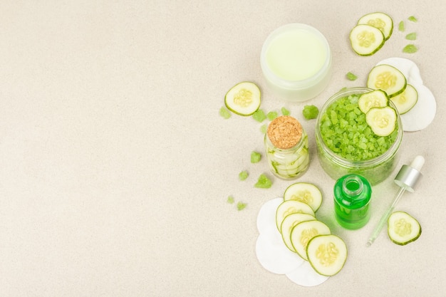 Cosmetici fatti in casa con cetriolo. Maschere vegetali disintossicanti per la pelle. Crema naturale, sale marino, lozione per il viso e acqua tonica. Sfondo di pietra chiara in cemento, vista dall'alto