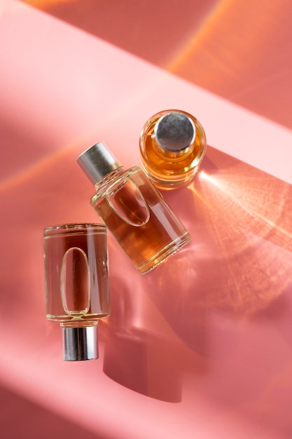 Cosmetici in bottiglia di vetro con olio per la bellezza o la cura della pelle su sfondo rosa luce solare naturale e sfumature vista dall'alto