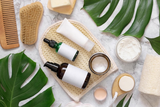 Cosmetici naturali e accessori per la cura della pelle e dei capelli vicino al mockup di foglie di monstera