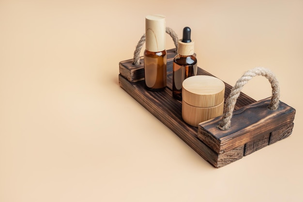 Cosmetici naturali in confezioni di bambù e vetro su vassoio di legno su sfondo beige con spazio per il testo Set di prodotti di bellezza organici SPA Concetto di cura della pelle