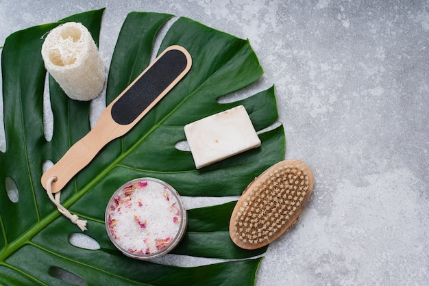 Cosmetici naturali per il bagno sullo sfondo di una foglia di palma. Sapone, sale da bagno, panno di luffa.
