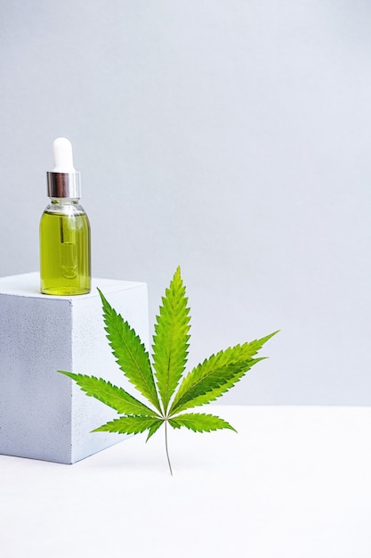 Cosmetici Olio di CBD e foglie di cannabis Natura morta moderna di bottiglie di vetro con olio di canapa