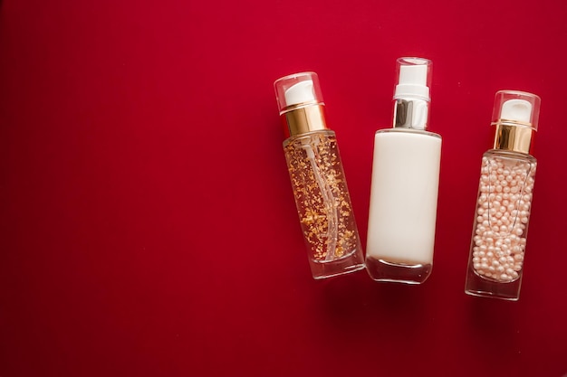 Cosmetici per la cura della pelle e prodotti di bellezza antietà bottiglie per la cura della pelle di lusso olio siero e crema per il viso su sfondo rosso