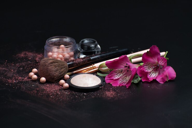 Cosmetici piatti e pennelli per il trucco su una superficie nera