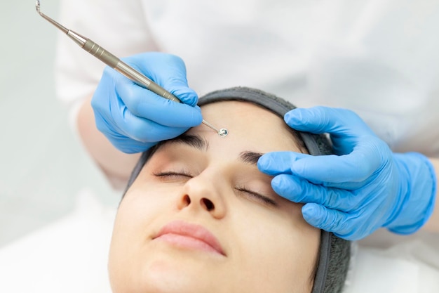 Cosmetologa fa la pulizia meccanica della pelle del viso di una ragazza in una clinica di cosmetologia