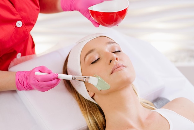 Cosmetologo che applica maschera sul viso della donna nel salone spa