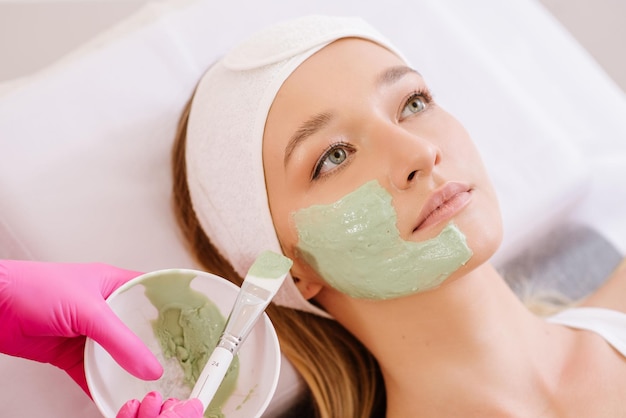 Cosmetologo che applica maschera sul viso della donna nel salone spa