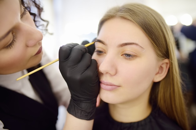 Cosmetologo che dipinge le sopracciglia a pennello.