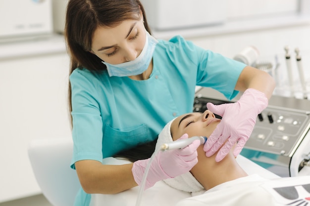 Cosmetologo femminile professionista che fa procedura hydrafacial nella clinica di cosmetologia. Uso medico